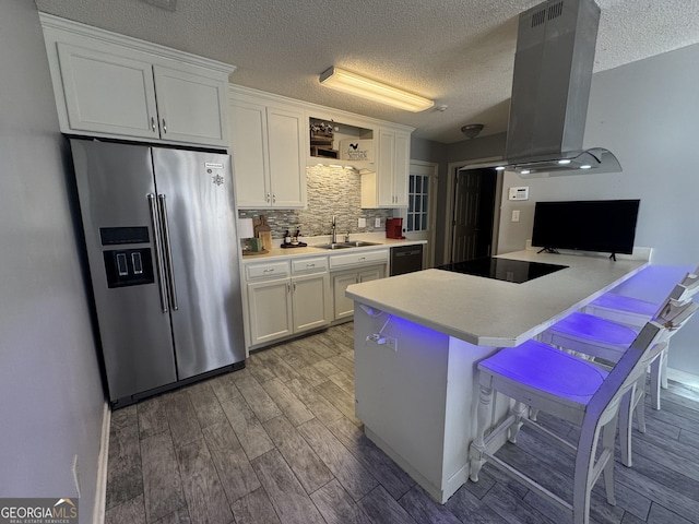 kitchen featuring island range hood, black appliances, a kitchen bar, white cabinets, and sink