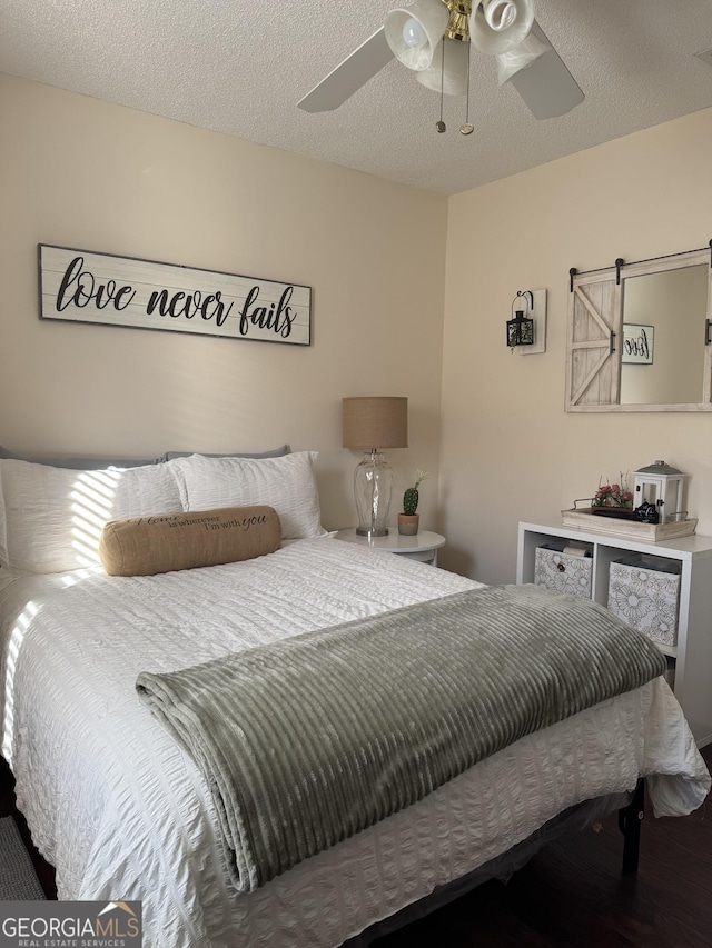 bedroom featuring a textured ceiling, ceiling fan, and a barn door