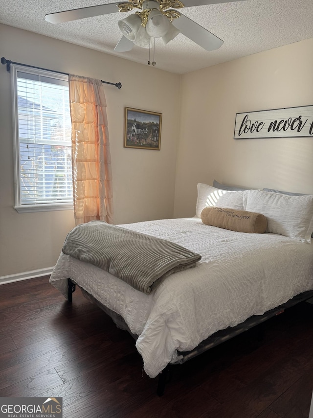 bedroom with ceiling fan, a textured ceiling, and dark hardwood / wood-style floors