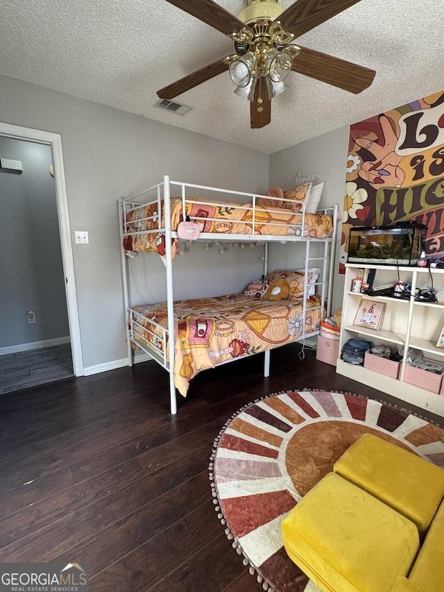 bedroom featuring ceiling fan, hardwood / wood-style floors, and a textured ceiling