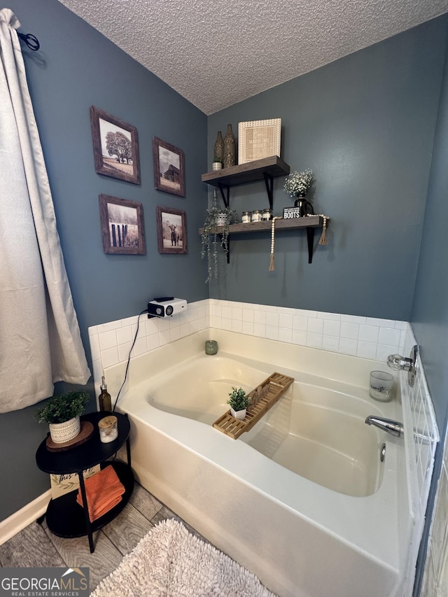 bathroom featuring tile patterned floors, a textured ceiling, and a tub to relax in