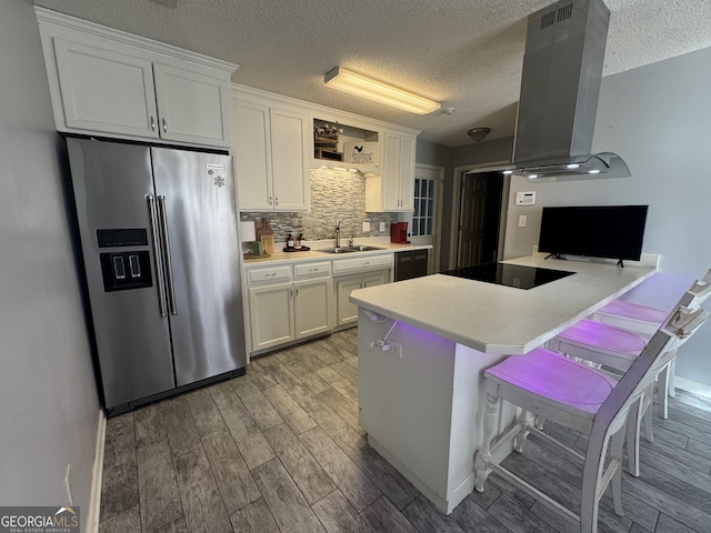 kitchen featuring island exhaust hood, black electric cooktop, high end refrigerator, white cabinets, and sink