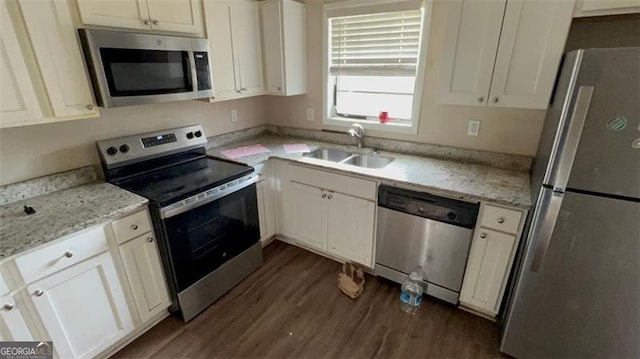 kitchen with white cabinets, sink, light stone counters, appliances with stainless steel finishes, and dark hardwood / wood-style flooring