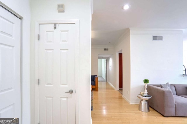 hall with crown molding and light hardwood / wood-style flooring