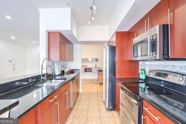 kitchen featuring dark stone counters, track lighting, sink, appliances with stainless steel finishes, and light tile patterned flooring