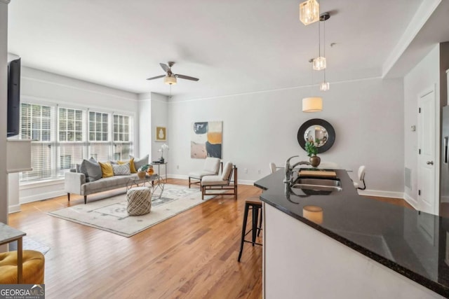 living room with ceiling fan, sink, and light hardwood / wood-style flooring