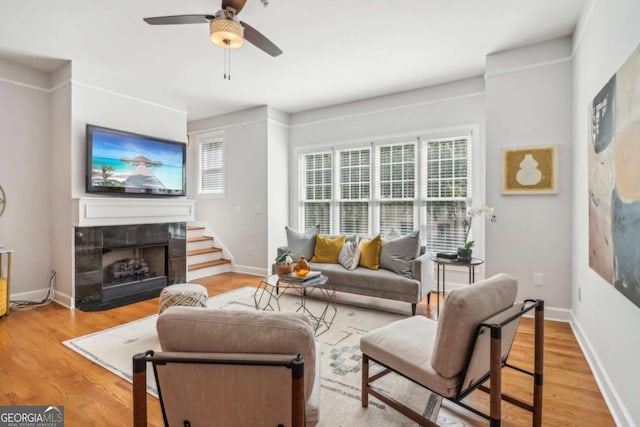 living room featuring a wealth of natural light, a fireplace, ceiling fan, and light wood-type flooring