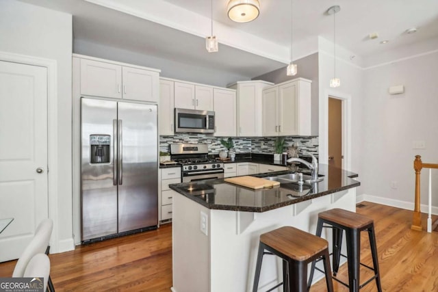 kitchen featuring sink, white cabinets, decorative light fixtures, and appliances with stainless steel finishes