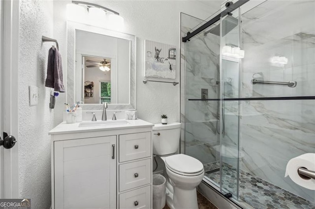 bathroom featuring vanity, toilet, an enclosed shower, and ceiling fan