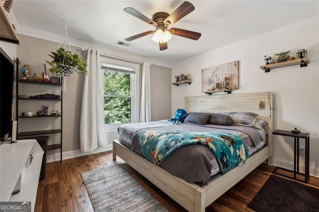 bedroom featuring dark hardwood / wood-style flooring, ceiling fan, and ornamental molding