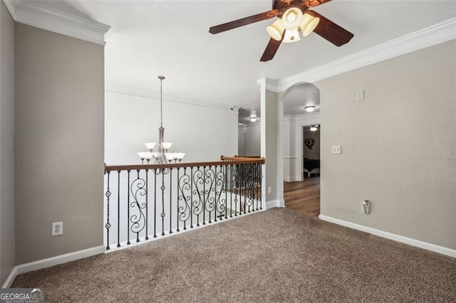 carpeted spare room with ceiling fan with notable chandelier and crown molding