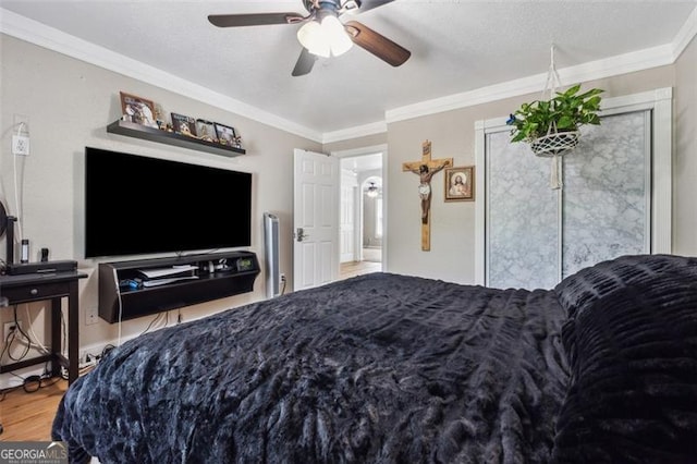 bedroom with hardwood / wood-style floors, ceiling fan, crown molding, and a textured ceiling