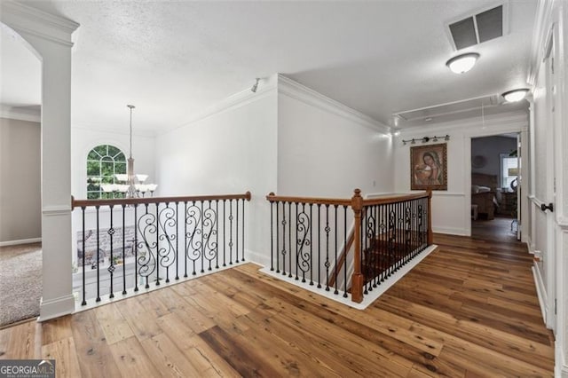 hallway featuring crown molding, a chandelier, a textured ceiling, and hardwood / wood-style flooring