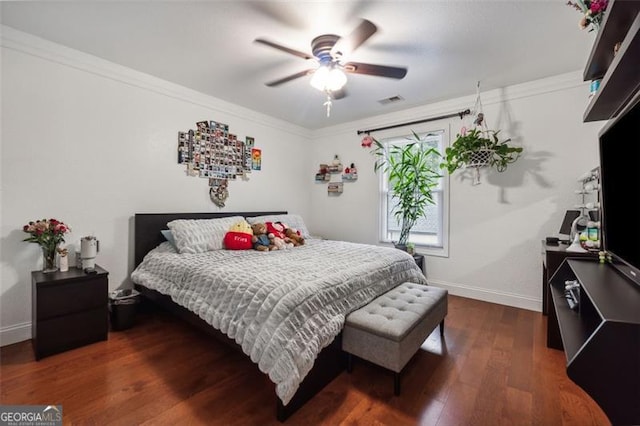 bedroom featuring dark hardwood / wood-style flooring, ceiling fan, and ornamental molding