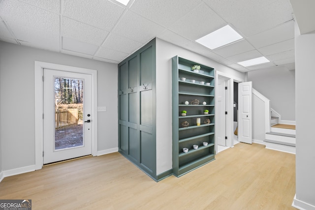 interior space featuring a drop ceiling, built in features, green cabinets, and wood-type flooring