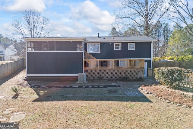 rear view of house with a sunroom, a yard, and a deck