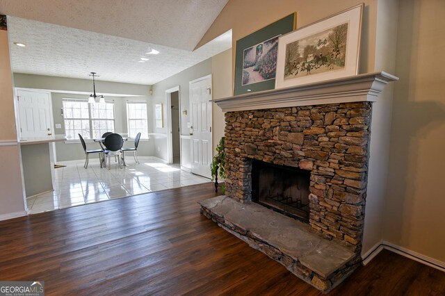 tiled living room with a fireplace, a textured ceiling, and vaulted ceiling