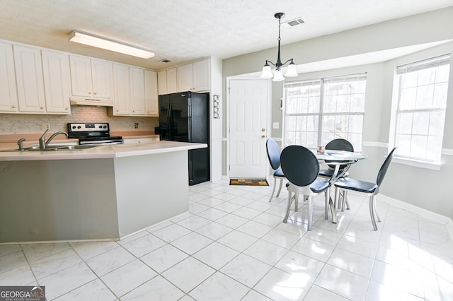 kitchen with black refrigerator, sink, electric stove, white cabinetry, and hanging light fixtures