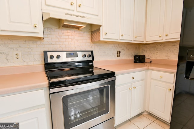 kitchen featuring light tile patterned floors, black fridge, white cabinetry, and stainless steel range with electric cooktop