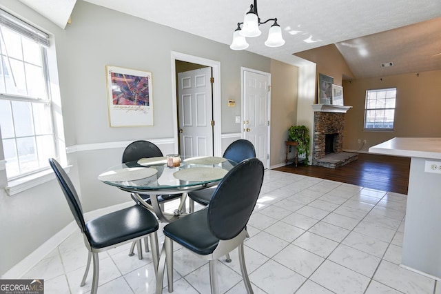 dining space featuring plenty of natural light, a fireplace, and vaulted ceiling