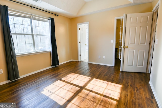 unfurnished bedroom featuring multiple windows, lofted ceiling, dark wood-type flooring, and a textured ceiling