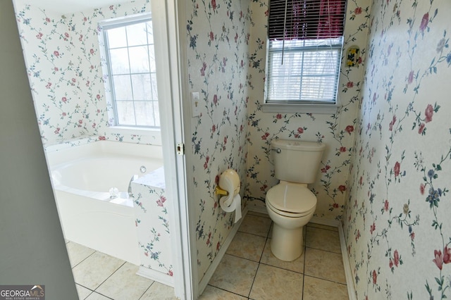 bathroom featuring tile patterned flooring, a bathing tub, toilet, and a wealth of natural light