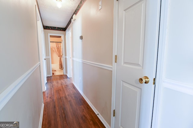 hallway with dark hardwood / wood-style floors and a textured ceiling