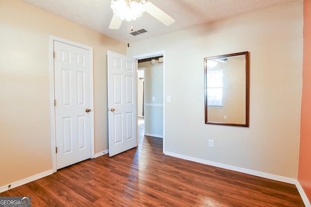 unfurnished bedroom featuring a textured ceiling, ceiling fan, and dark wood-type flooring