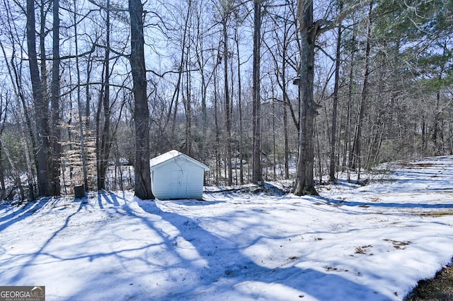 snowy yard featuring a storage unit