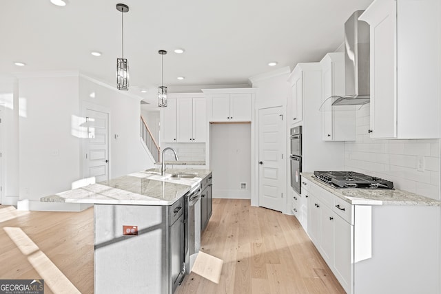 kitchen with a center island with sink, black gas stovetop, sink, light stone countertops, and white cabinetry