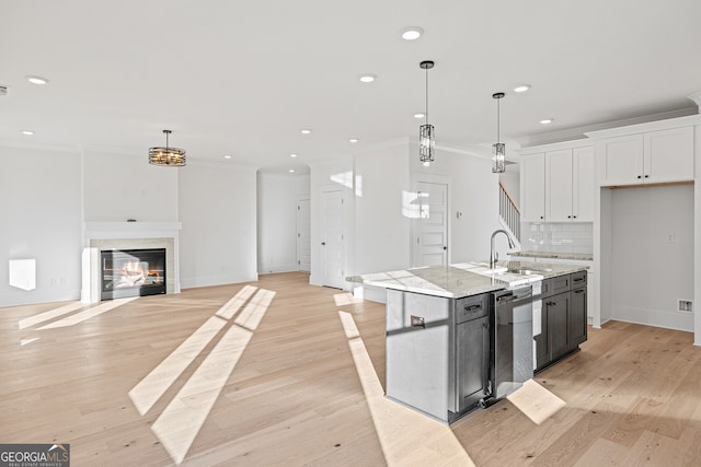 kitchen featuring pendant lighting, light hardwood / wood-style floors, white cabinetry, and an island with sink