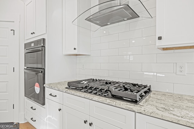 kitchen featuring light stone countertops, white cabinetry, black appliances, and exhaust hood