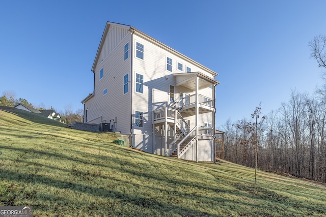 rear view of property featuring central AC, a yard, a balcony, and a deck