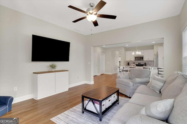 living room featuring hardwood / wood-style floors and ceiling fan with notable chandelier