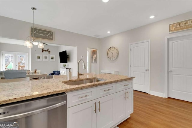 kitchen with pendant lighting, sink, stainless steel dishwasher, light stone counters, and white cabinetry