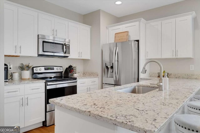 kitchen with a kitchen breakfast bar, white cabinetry, and stainless steel appliances