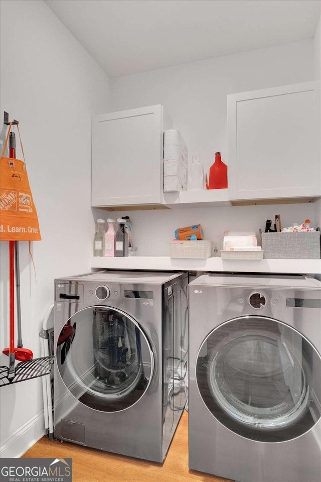 laundry room with cabinets, light hardwood / wood-style flooring, and washer and clothes dryer