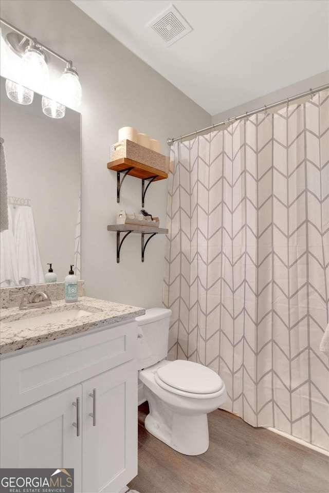 bathroom with hardwood / wood-style floors, vanity, toilet, and a shower with curtain