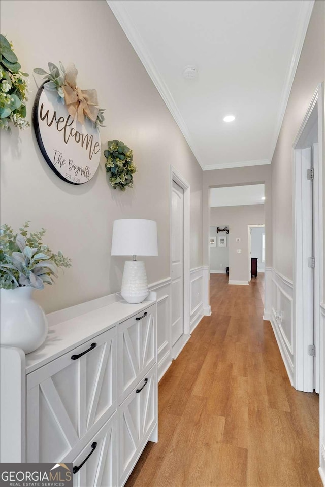 hallway with crown molding and light hardwood / wood-style flooring