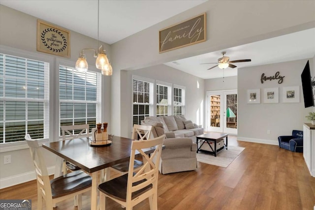 dining room with ceiling fan with notable chandelier, a healthy amount of sunlight, and light wood-type flooring