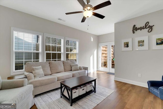 living room with a wealth of natural light, ceiling fan, and wood-type flooring