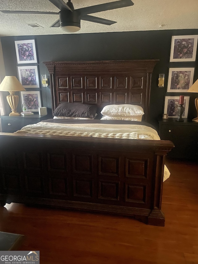 bedroom featuring dark hardwood / wood-style flooring, a textured ceiling, and ceiling fan