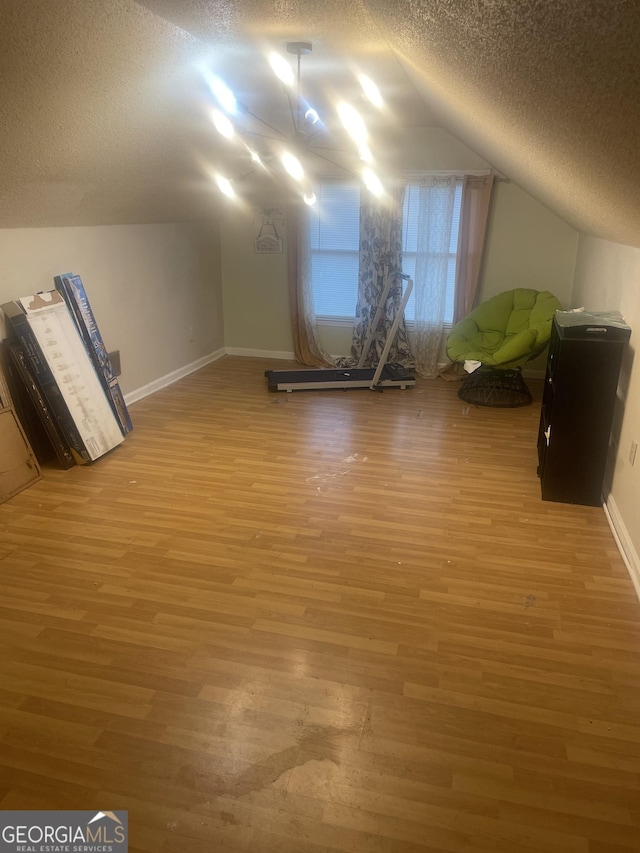 bonus room featuring vaulted ceiling, wood-type flooring, and a textured ceiling