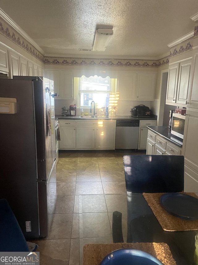 kitchen with stainless steel dishwasher, white cabinets, and fridge