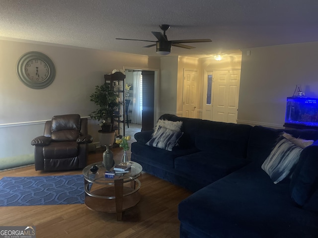 living room featuring hardwood / wood-style flooring, ceiling fan, and a textured ceiling