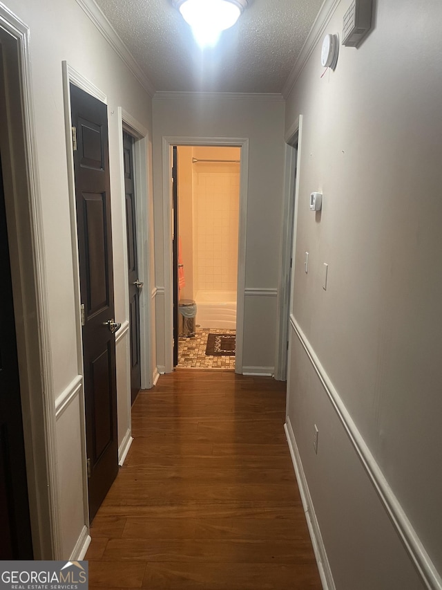 hall with a textured ceiling, crown molding, and dark hardwood / wood-style floors