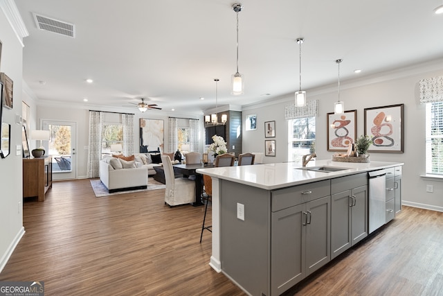 kitchen featuring dishwasher, decorative light fixtures, a center island with sink, and sink