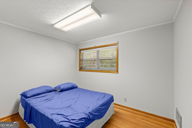 bedroom featuring hardwood / wood-style floors, a textured ceiling, and ornamental molding