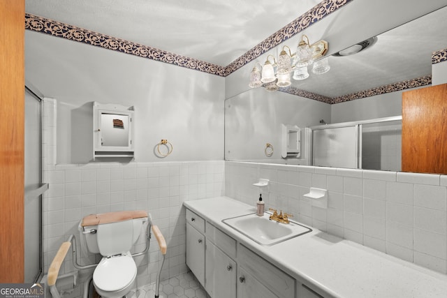 bathroom with vanity, a shower with door, tile patterned floors, toilet, and tile walls