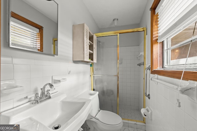 bathroom featuring a shower with door, sink, tile walls, tile patterned flooring, and toilet